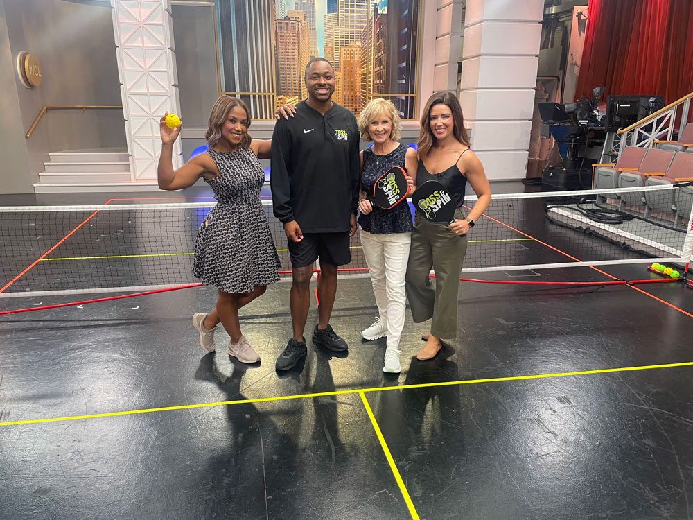 Founder of Toss and Spin Chris Clark and news anchors with pickleball paddles and ball.