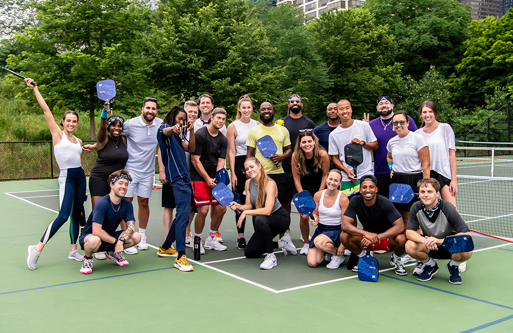 Group photo with pickleball paddles on a court.